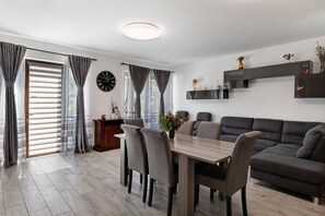 Una sala de estar moderna con una mesa de comedor, sillas, un sofá, un reloj y una chimenea.
