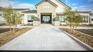 A modern building with a stone facade, large windows, and a central entrance. - Modern new home with luxury amenities.  (Mesa)