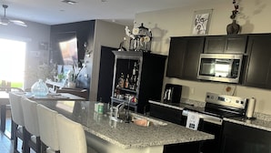 A modern kitchen with a central island, dark cabinetry, a microwave, and a dishwasher. - Modern new home with luxury amenities.  (Mesa)