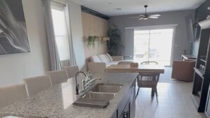 A modern kitchen with a central island, built-in appliances, and a dining area with a bench. - Modern new home with luxury amenities.  (Mesa)