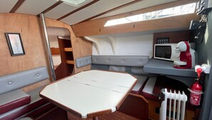 Un interior compacto con una mesa, asientos acolchados, un microondas y un extintor.