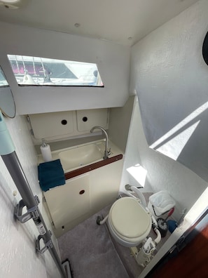 Et lille badeværelse med vindue, vask, toilet og et spejl.