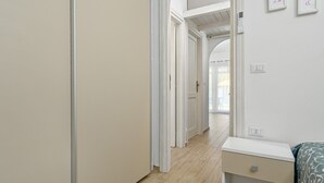 Een slaapkamer met een bed, nachtkastje, deur en een gang naar een andere kamer.