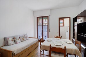 Quarto com uma cama, uma mesa de jantar posta para dois e uma televisão.