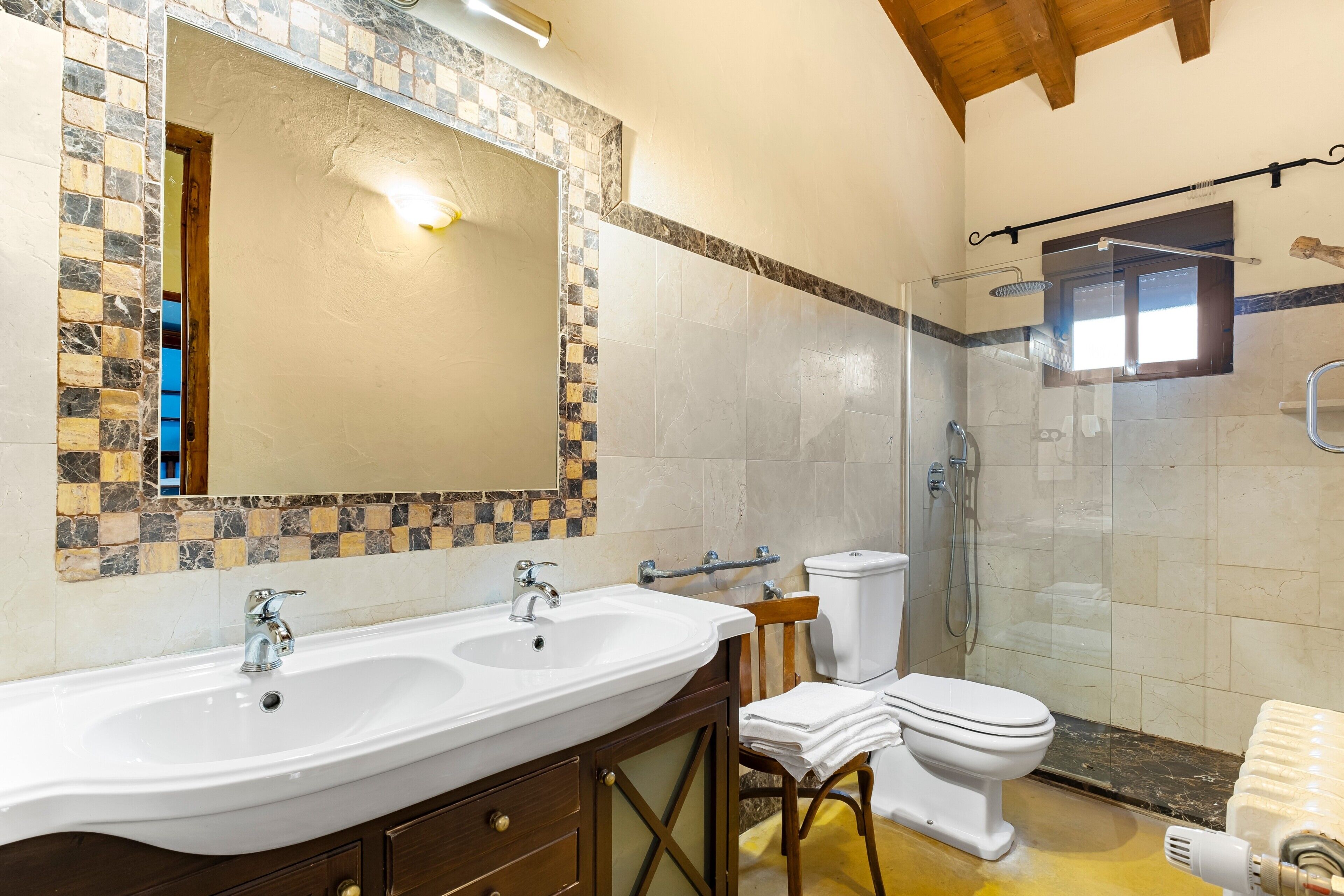 Een badkamer met een grote spiegel, twee wasbakken, een toilet en een douche.