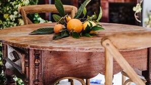 A wooden dining table with chairs, surrounded by lush greenery and a fireplace in the background. - Country House 'La Carrasca - Limón' with Shared Pool, Wi-Fi and Air Conditioning (Catral)