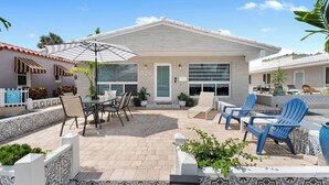 A modern house with a patio area featuring outdoor furniture, a covered seating area, and a number '326' sign.
