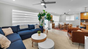 A modern living room with a blue sofa, a round coffee table, and a ceiling fan.