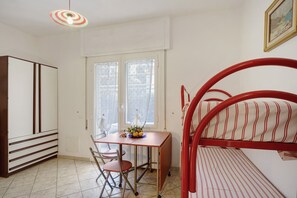 Una stanza arredata con un letto, un tavolo con sedie, un armadio e una finestra.