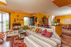 Kodikas olohuone, jossa on sohva, ruokailutila ja keittiö.