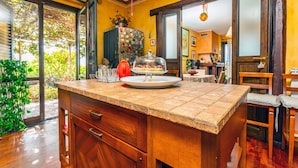 Una cocina con una isla de madera, un refrigerador adornado con imanes y una puerta de vidrio que da a un patio.