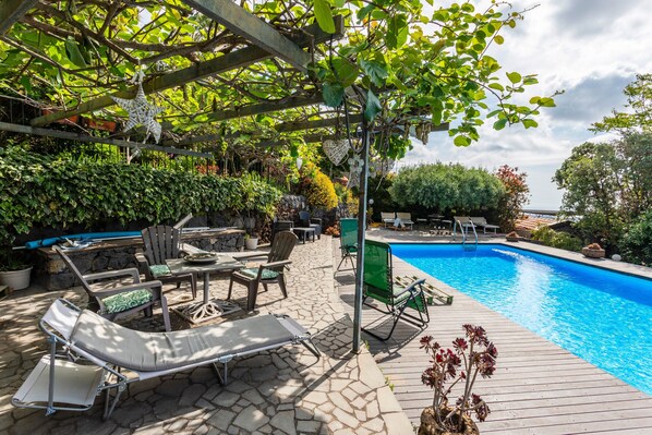 Uma área junto à piscina com espreguiçadeiras, um pérgola e uma piscina.
