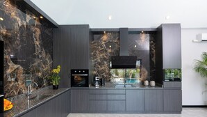 Eine moderne Küche mit dunklen Schränken, einer Marmor-Spritzschutzleiste und einem eingebauten Backofen.