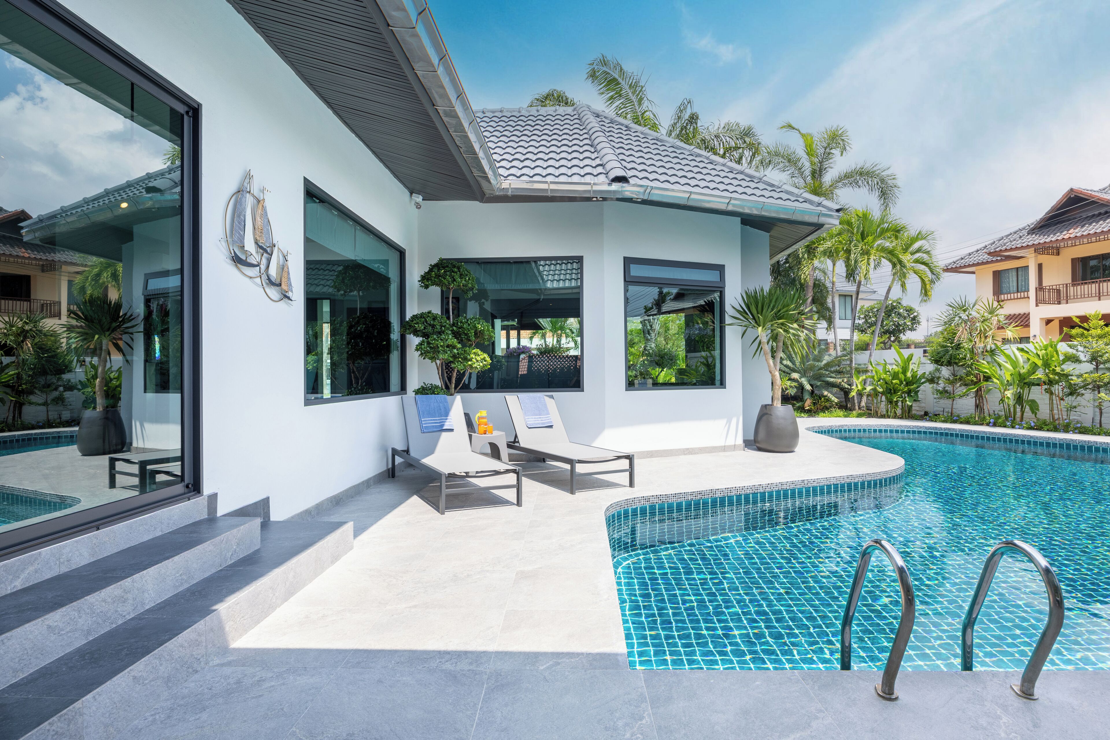 A modern house with a swimming pool, large windows, and outdoor seating.