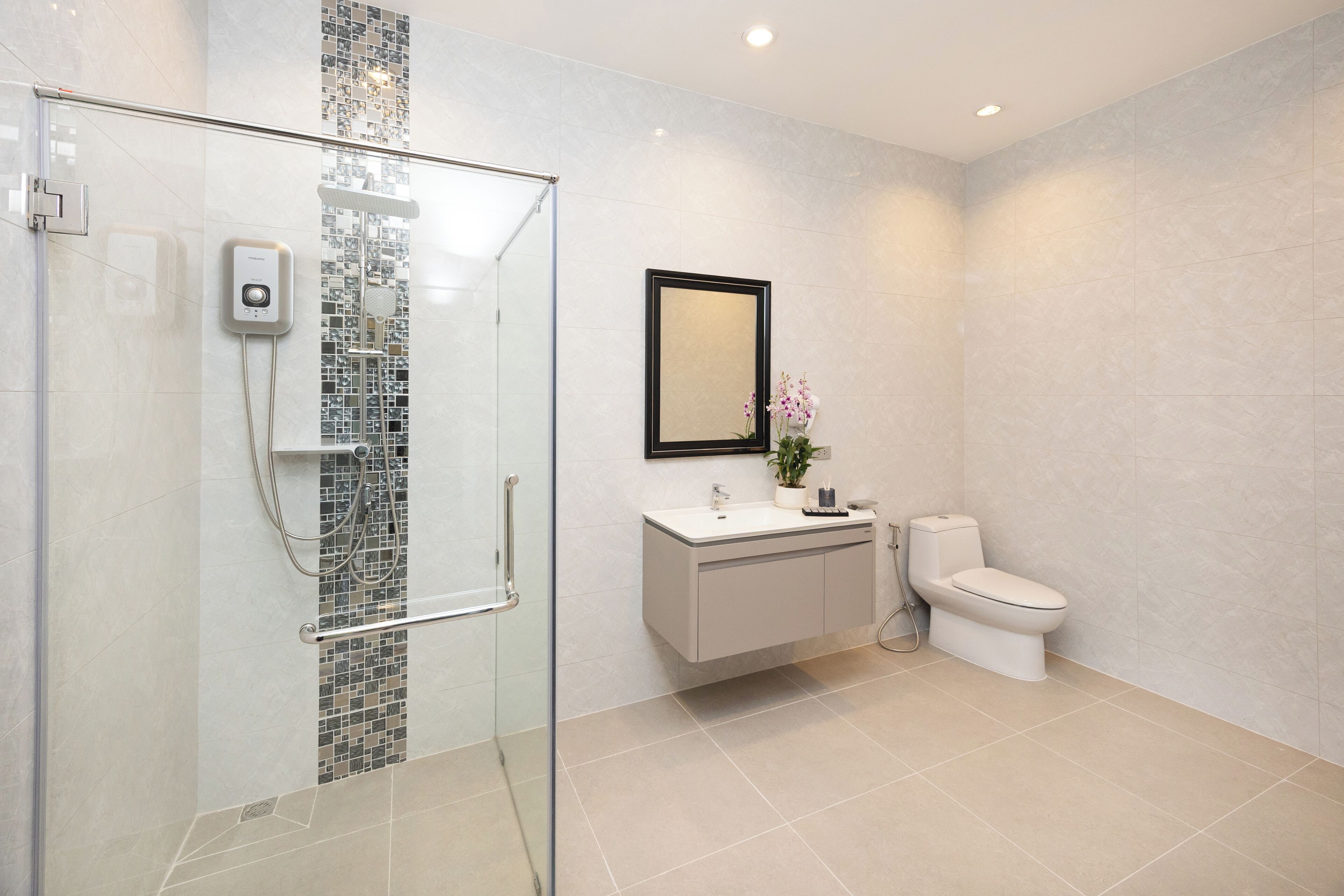 Un baño moderno con ducha de vidrio, un lavamanos blanco con espejo y un inodoro.