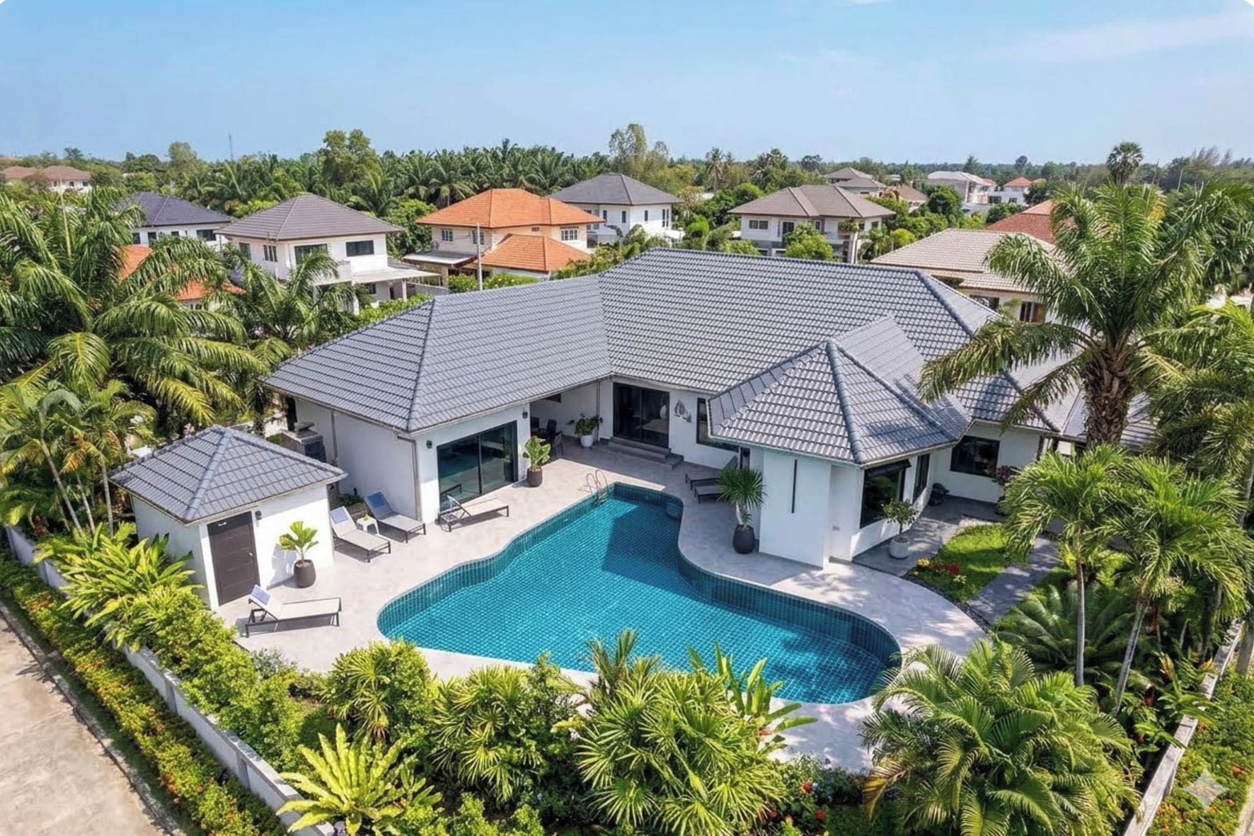 A residential property with a swimming pool, surrounded by lush greenery and palm trees.