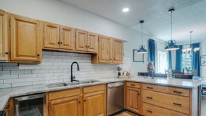 Una cocina moderna con armarios de madera, salpicadero de ladrillo blanco, electrodomésticos de acero inoxidable y una isla grande con pileta.