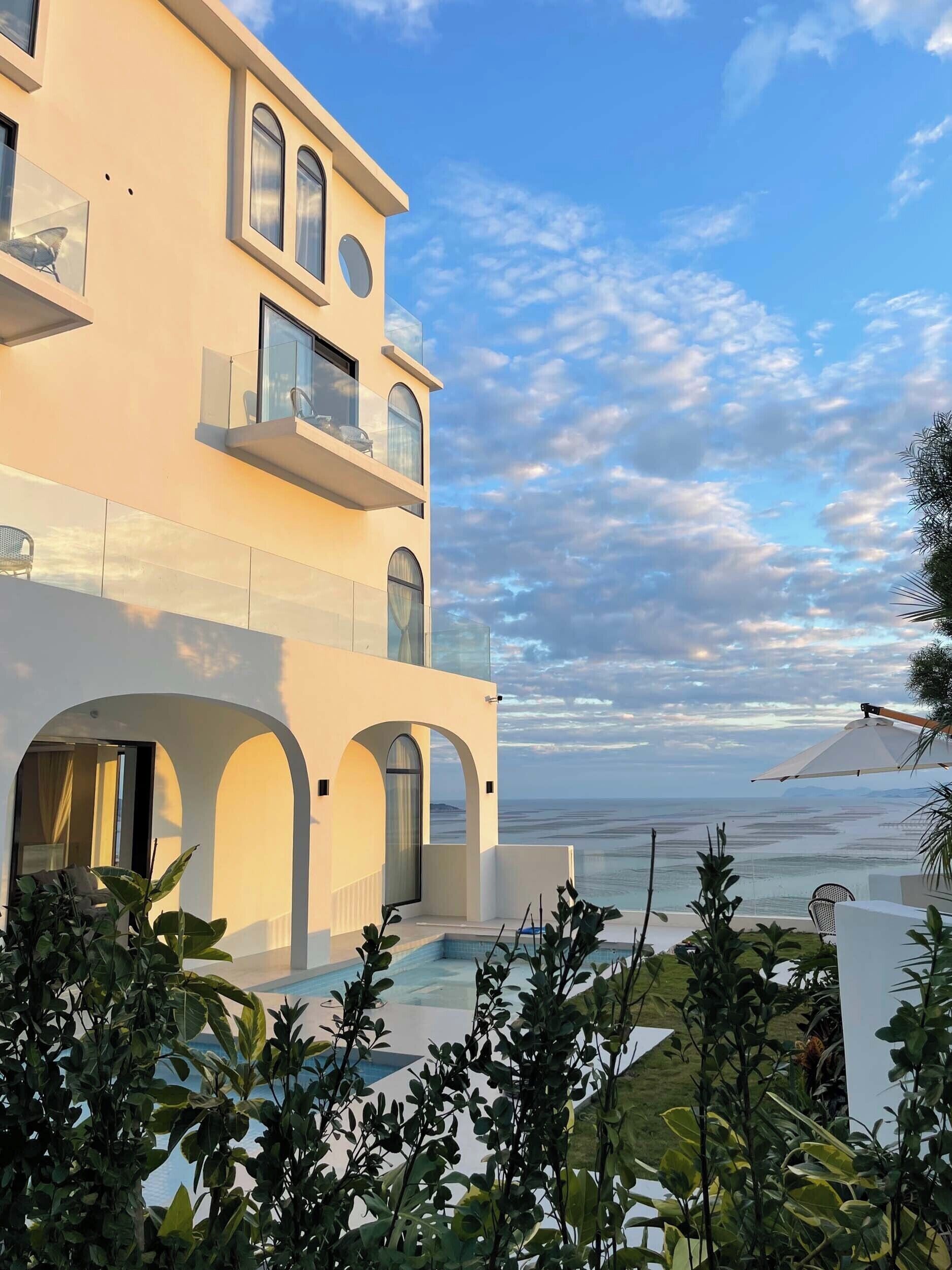 A modern multi-story building with a pool and a view of the sea.