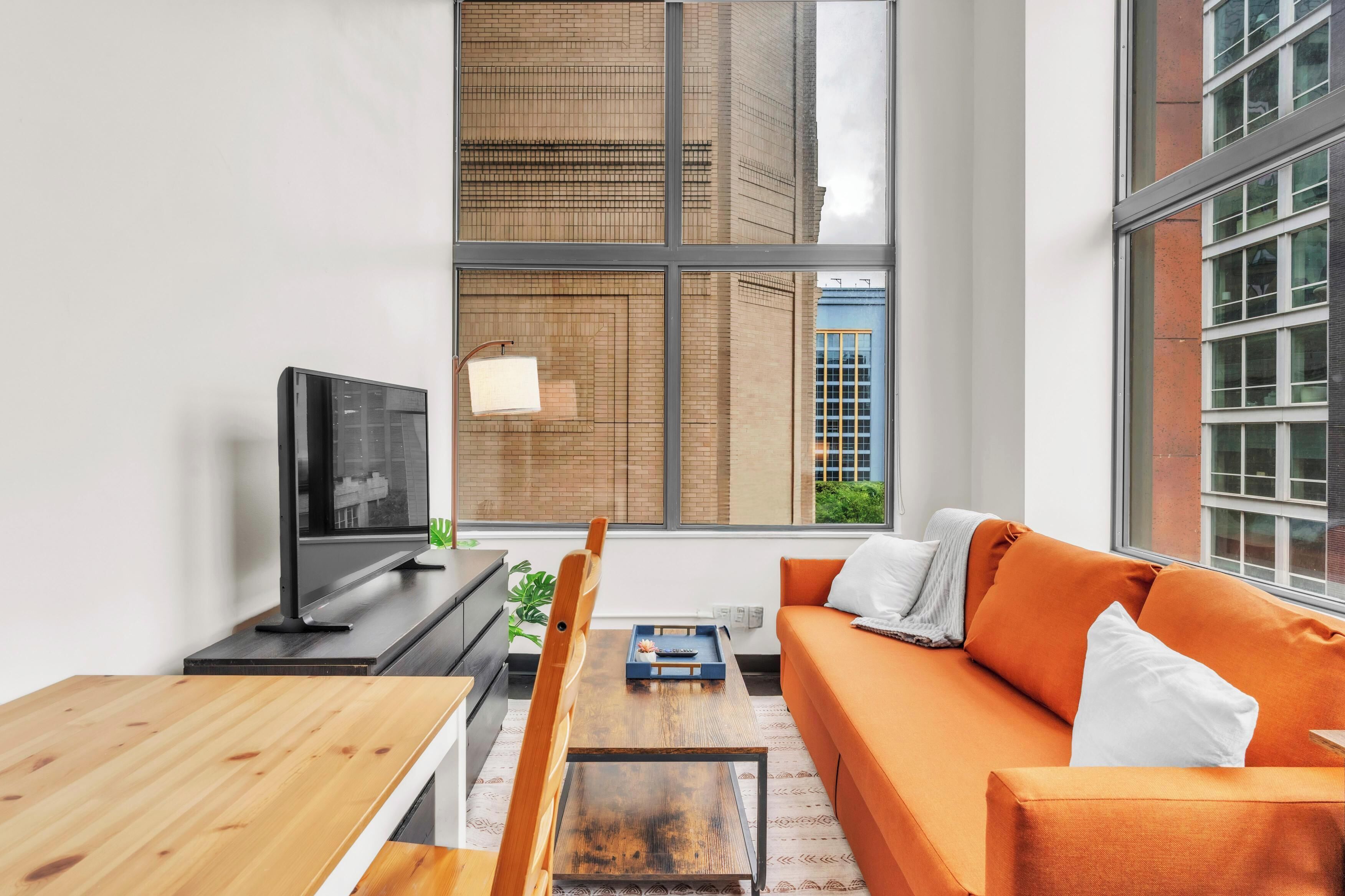 Una sala de estar moderna con un ventanal grande, un sofá, una mesa de centro y un televisor.