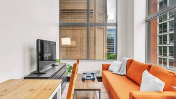 Una sala de estar moderna con un ventanal grande, un sofá, una mesa de centro y un televisor.