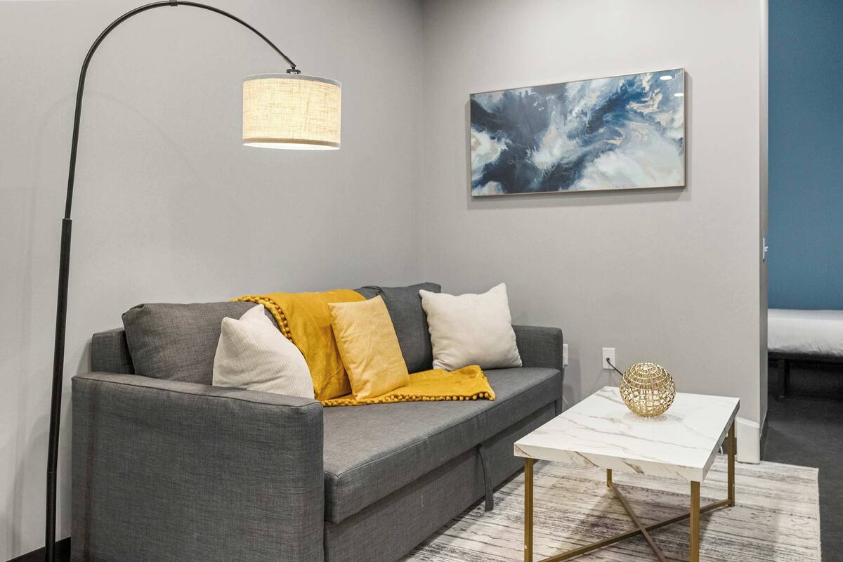 A modern living room with a grey sofa, a white coffee table, and a floor lamp.