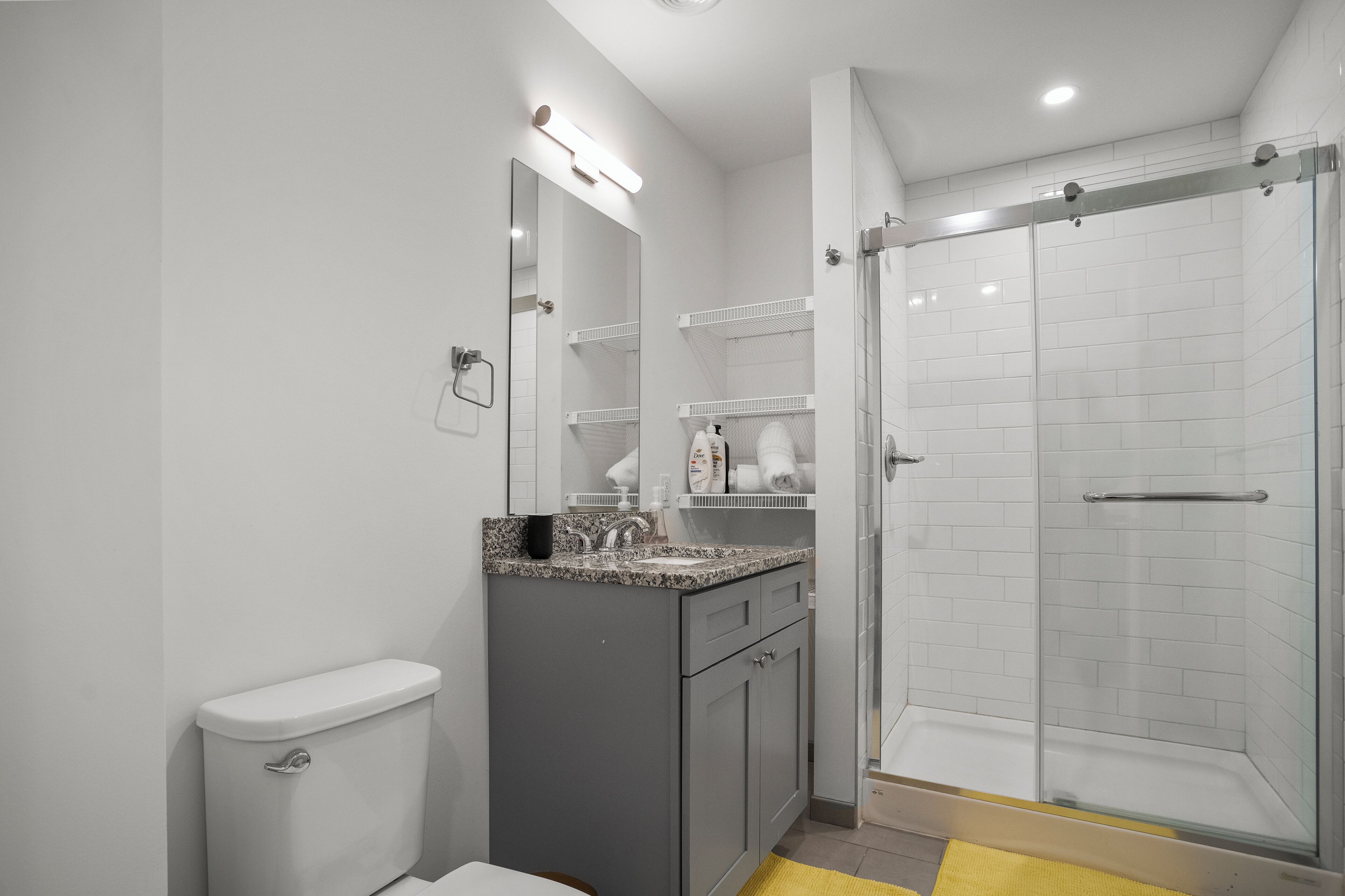 A modern bathroom with a toilet, a sink with a mirror, and a glass-enclosed shower.
