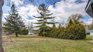 A residential yard with a lawn, several trees, and a house in the background. - 5 min to the beach! Sun filled cottage in Turkey Point (Vittoria)