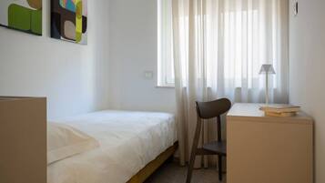 Een slaapkamer met een bed, een bureau en een stoel.