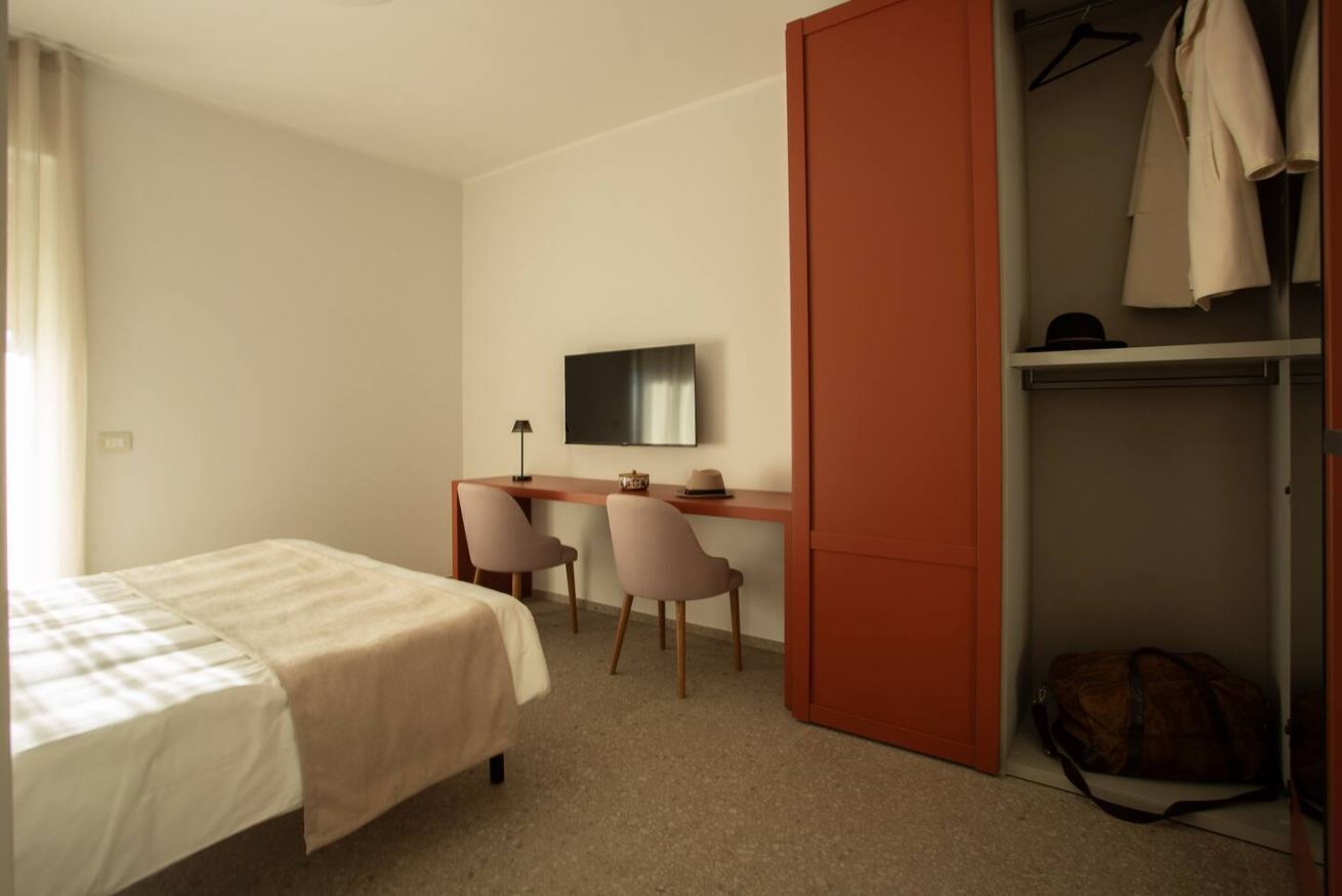 Una camera da letto con un letto, una scrivania con due sedie, una televisione e un armadio.