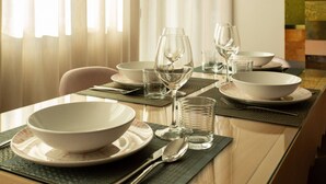 A dining table set with white bowls, wine glasses, and water glasses, with a view of a window with sheer curtains. - Palazzo Indaco - RESIDENZA PERLA (Castel di Sangro)