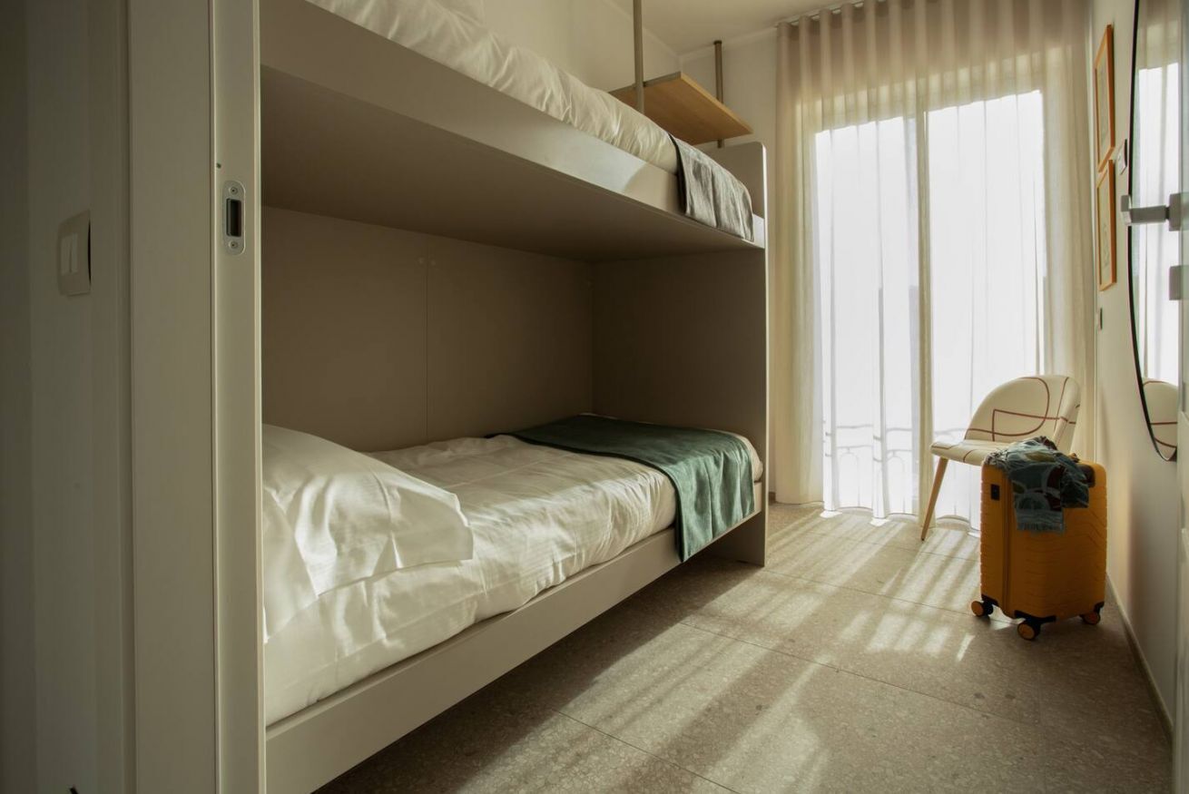 A bunk bed room with a single bed, a chair, and a suitcase.