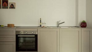 A kitchen with a built-in oven, a sink, and a countertop with a bottle and glasses. - Palazzo Indaco - RESIDENZA PERLA (Castel di Sangro)