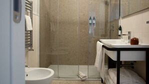 A modern bathroom with a glass-enclosed shower, a white sink, and a towel rack. - Palazzo Indaco - RESIDENZA RUBINO (Castel di Sangro)