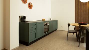 Una cucina con mobili color petrolio, una macchina da caffè e un piano cottura.