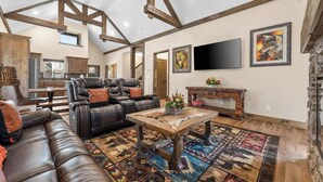 A spacious living room with a leather sofa, a coffee table, and a fireplace. - HUGE Private Heated Swim Spa • Game Room • 7BR/7BA • Entire home • Work Space (Hollister)