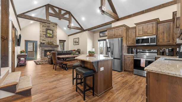 A spacious kitchen with wooden beams, a stone fireplace, and modern appliances. - HUGE Private Heated Swim Spa • Game Room • 7BR/7BA • Entire home • Work Space (Hollister)