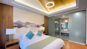 A modern hotel room with a large bed, a nightstand, a wall-mounted lamp, and a view of the bathroom through a glass door. - Lin an Hot Spring Story Family Homestay (Hangzhou)