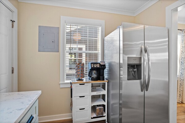 A compact kitchen with a stainless steel refrigerator, a coffee maker, and a small countertop. - Cottage Row: Daphne (Laurel)