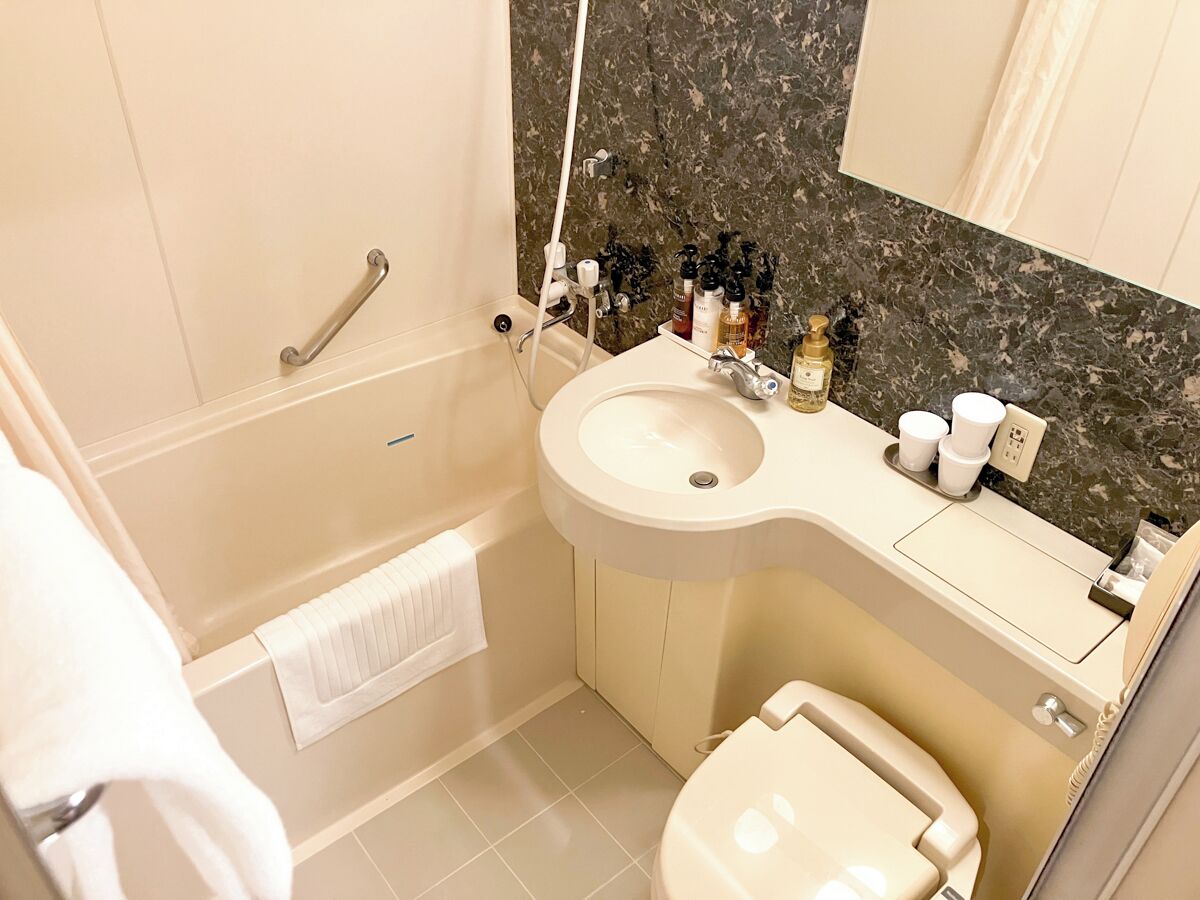 A bathroom with a bathtub, a sink, a toilet, and a vanity with toiletries.