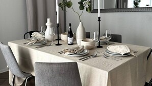 A dining table set for four with a neutral color scheme, white plates, and a vase with greenery. - Coastal Getaway Near Venice, FREE Parking (Marina del Rey)