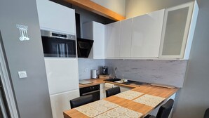 A modern kitchen with a central island, white cabinetry, and a built-in oven. - Apartment center Carmes (Toulouse)
