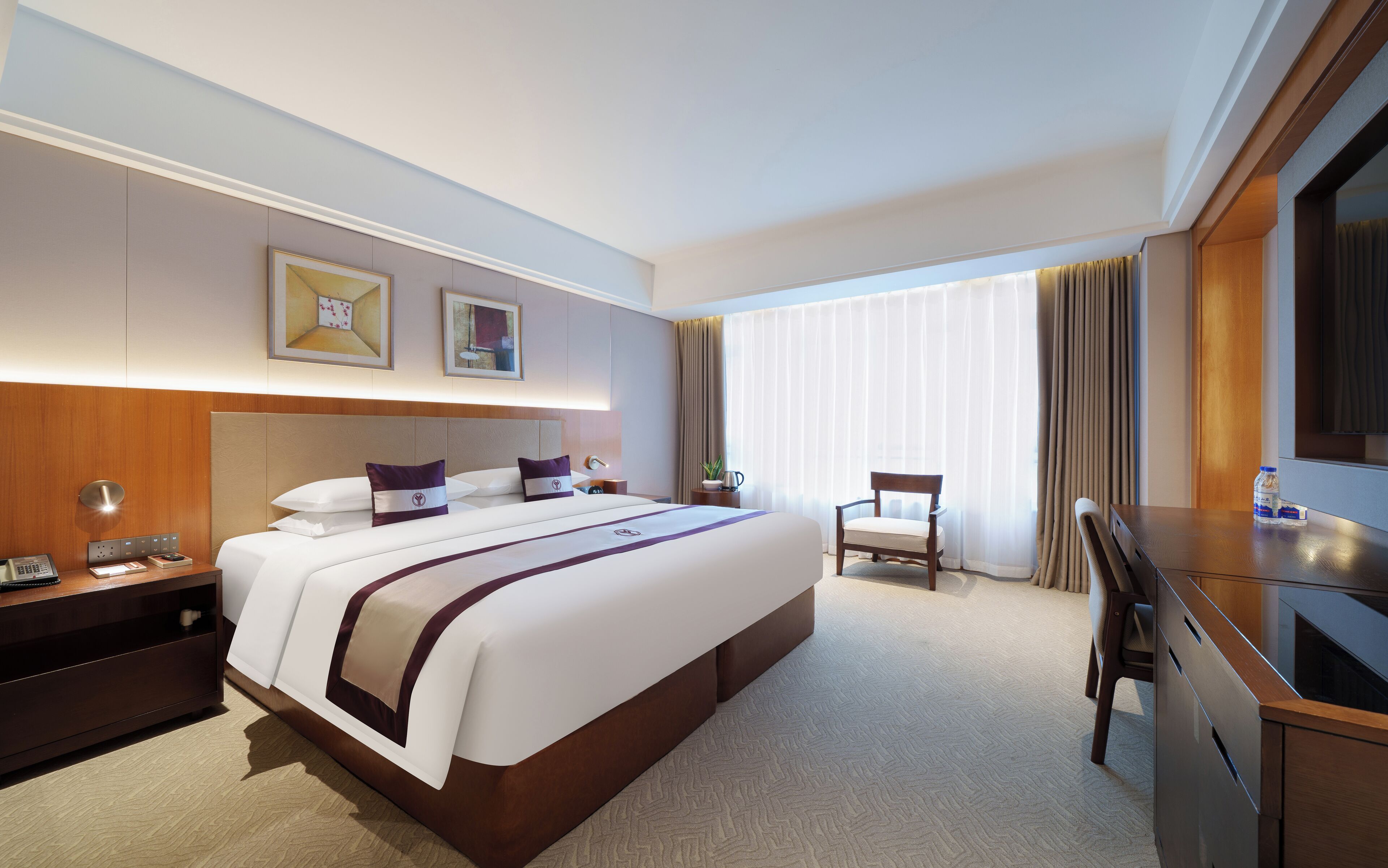 A hotel room with a large bed, bedside tables, a desk, and a chair.