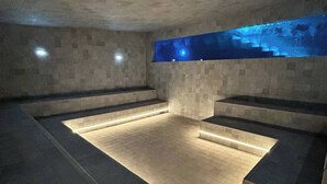 A modern spa with a stone floor, built-in seating, and a wall-mounted water feature. - Porto Alto Resort - Pé na Areia (Ipojuca)