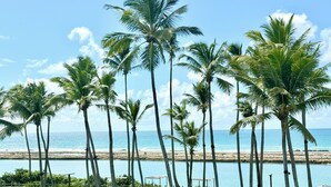 A beachside patio with tables and chairs, palm trees, and a view of the ocean. - Porto Alto Resort - Pé na Areia (Ipojuca)