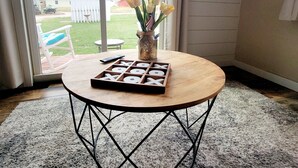 A room with a round table, a vase with flowers, and a tic-tac-toe board.