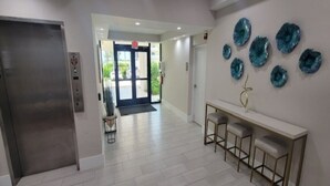 A hallway with a reception desk, bar stools, and a wall with decorative plates. - 1 bedroom plus STUDIO on Vanderbilt Beach. Beach access, water views. Sleeps 4 (Naples)