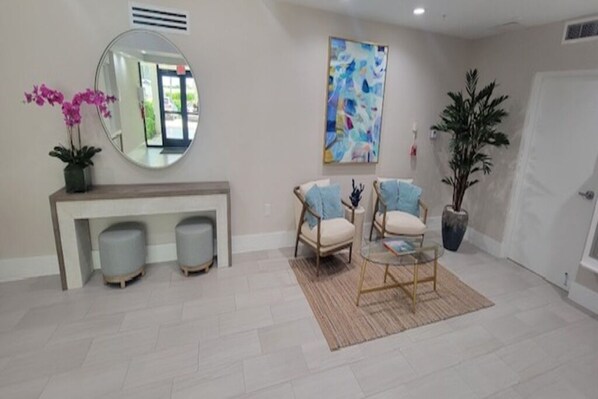 A modern living room with a round mirror, two armchairs, a coffee table, and a potted plant.