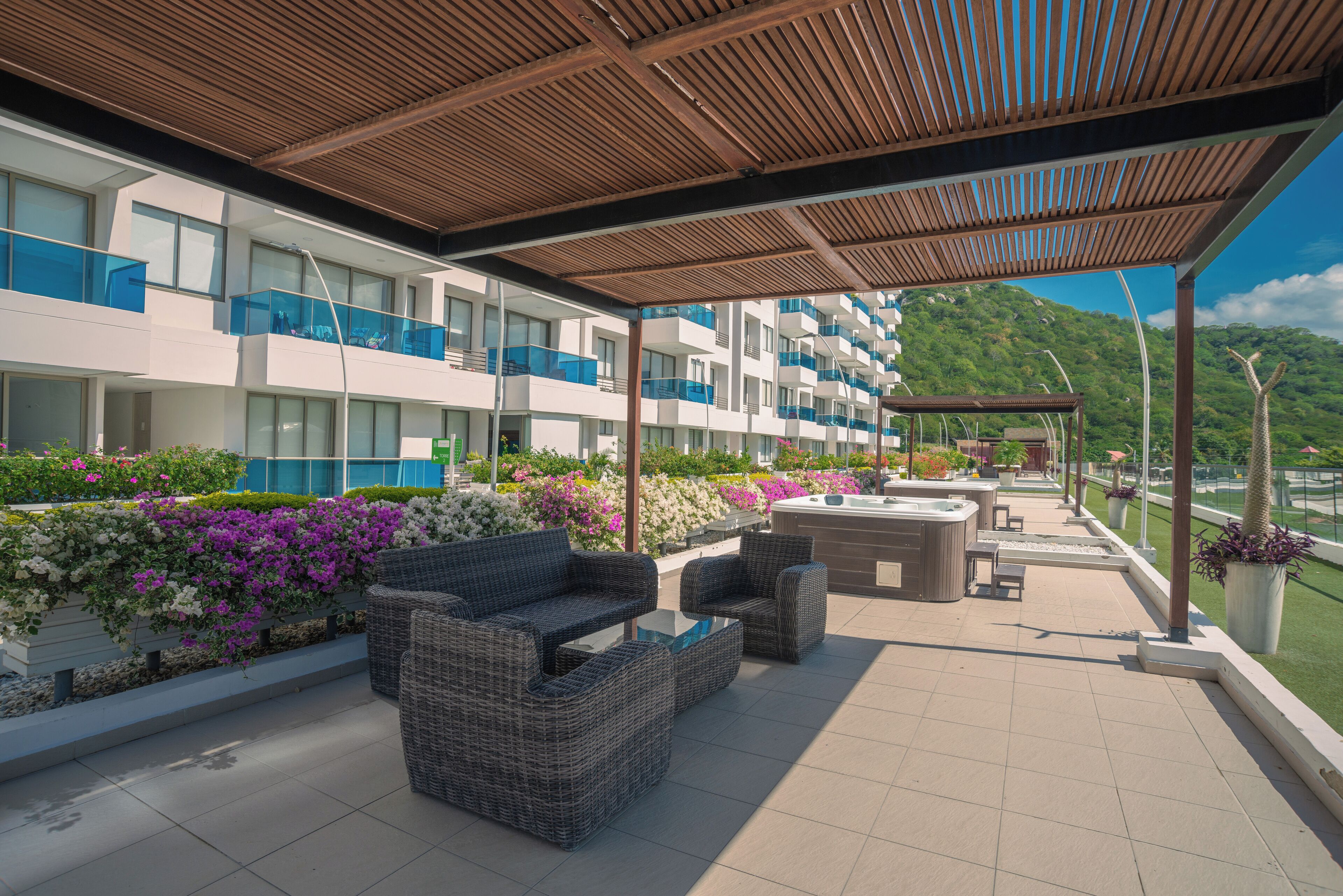 A covered outdoor seating area with wicker furniture, a bar, and a view of a mountain.
