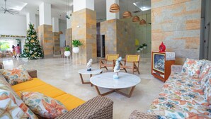 A lobby with a Christmas tree, wicker furniture, and a large stone wall. - Charming seafront 2-bedroom apartment with AC, WiFi in delightful Santa Marta (Santa Marta)