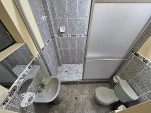 A compact bathroom with a shower, a sink, and a toilet.